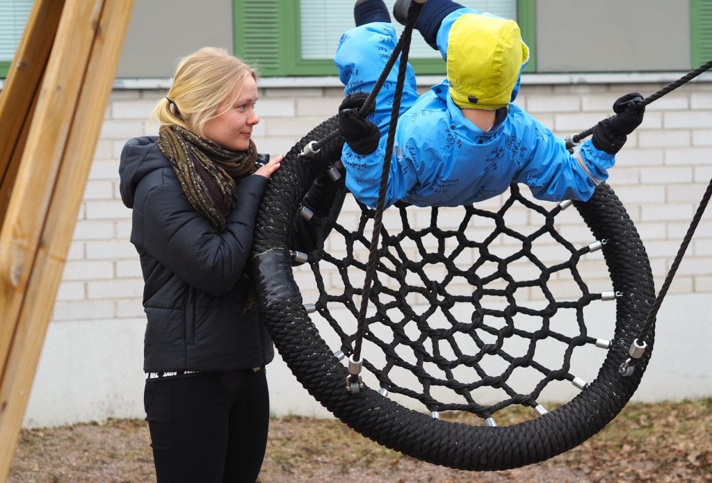 Ohjaaja ja lapsi ulkona hämähäkkikeinussa