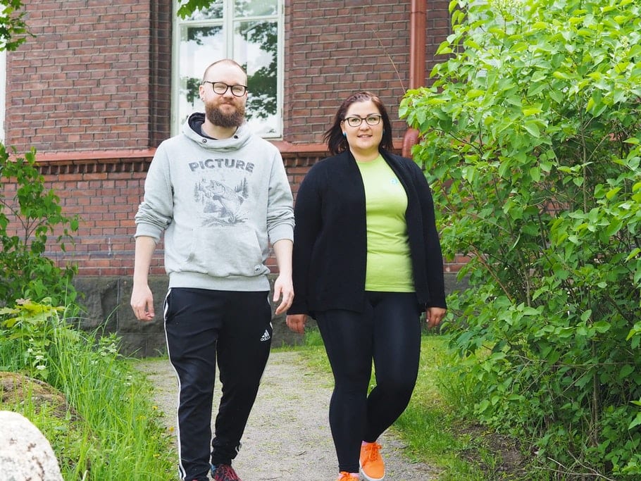 Joppe ja Mira kävelevät polkua pitkin vierekkäin punaisen tiilirakennuksen edessä.