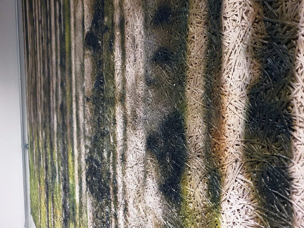 Lähikuva metsämaisemataulusta, jossa erottuu kuvan tekstuuri. Tekstuurissa punosmaista kuviointia.