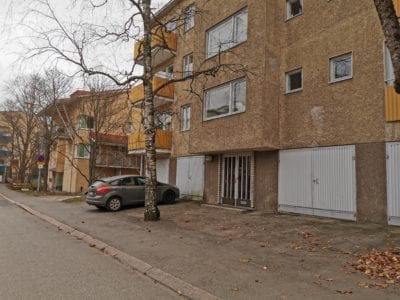 Kerrostalon julkisivu. Pihalla on auto parkissa.