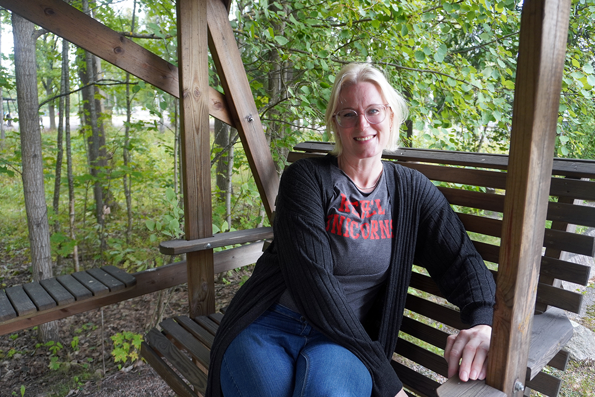 Liina Sievers istuu keinussa vihreiden puiden alla.